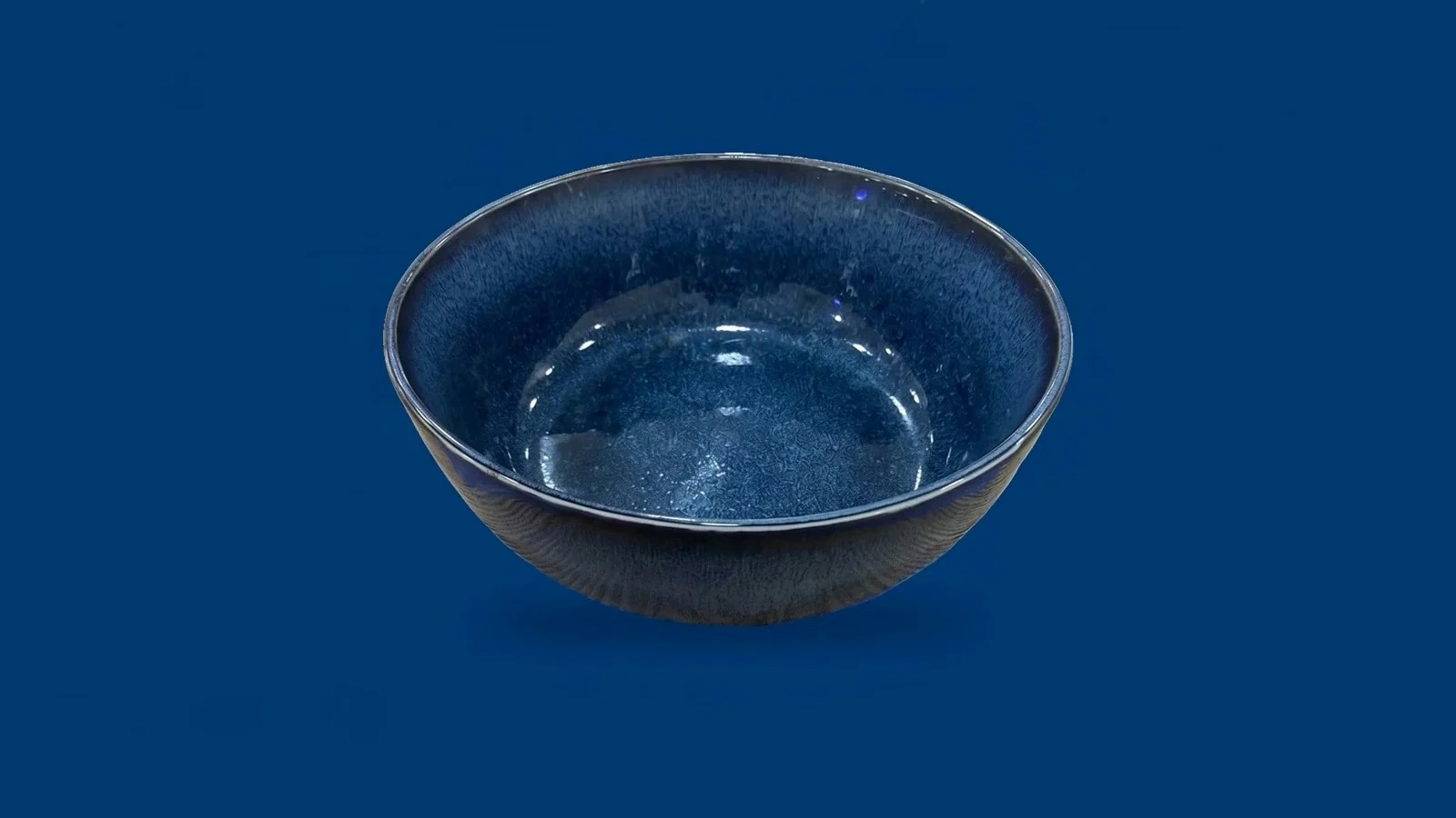 Un bol Salad'House en céramique bleu nuit, vide, posé sur fond bleu